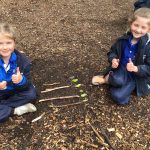 2 girls with their thumbs up in the forest