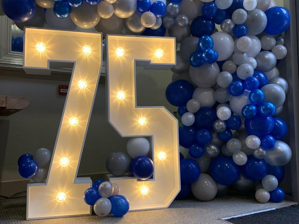 75 with blue and white balloons around it