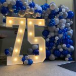 75 with blue and white balloons around it