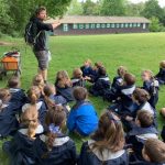 students listening to the teacher on the grass