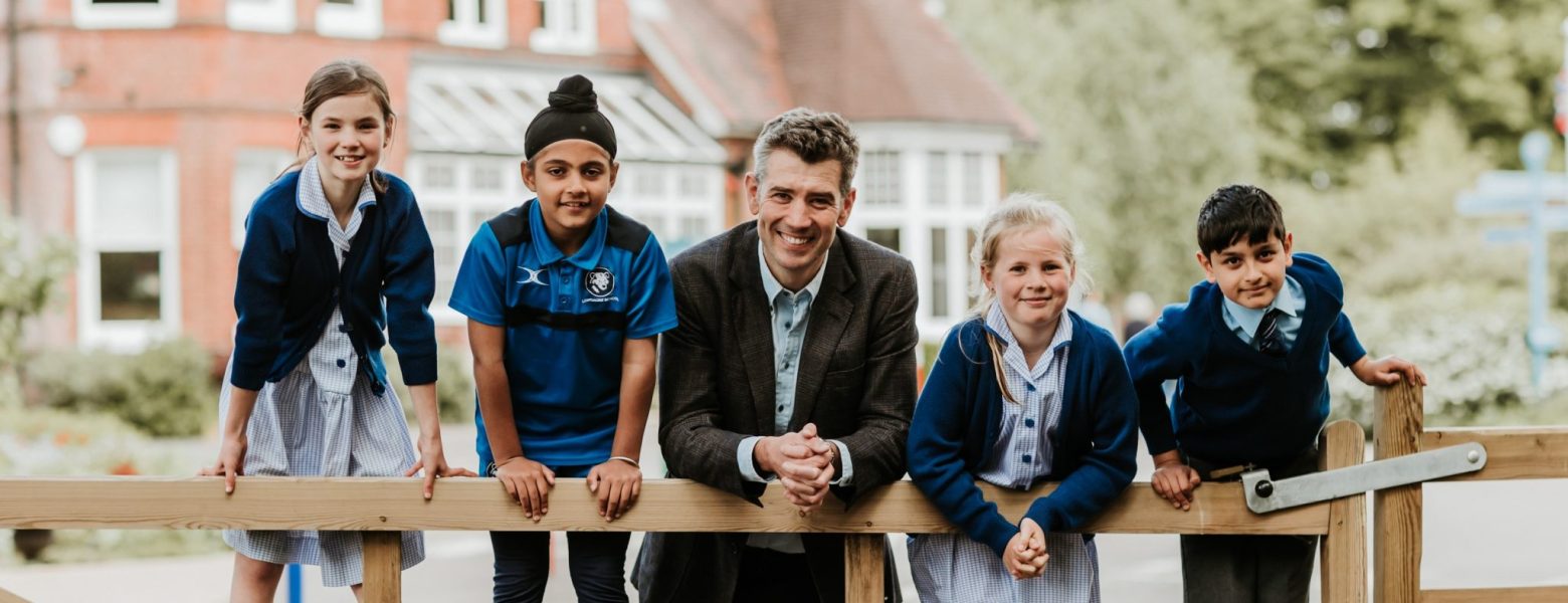 students and a teacher leaning on a fence