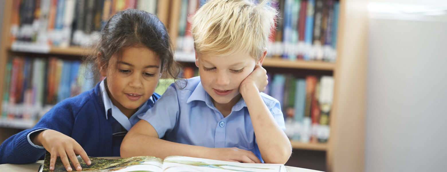 two students reading a book together