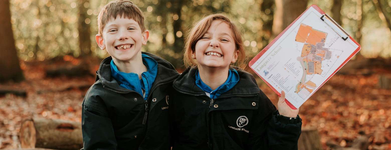 Two students in the outdoors smiling and studying