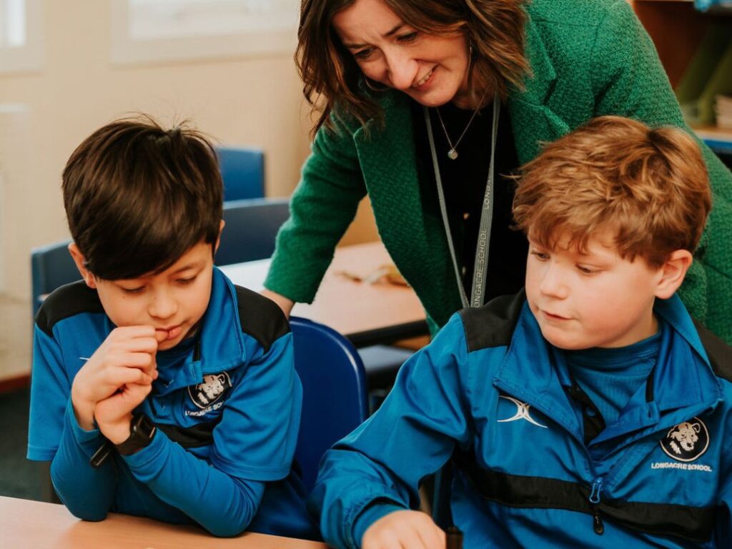 Teacher giving individual attention to two pupils in class