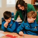 Teacher giving individual attention to two pupils in class