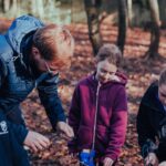 Teacher supports prep school children in outdoor learning using tools