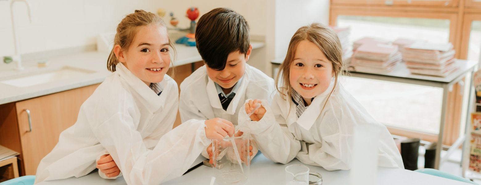 Three pupils in a prep school science lesson, engaging and having fun